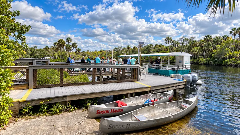 Wooden dock and tour boat beside a lush riverbank