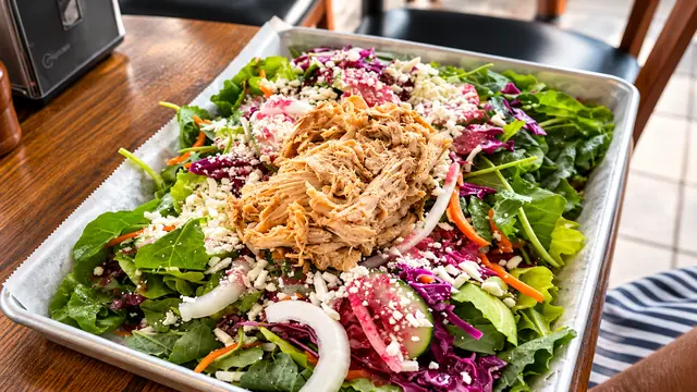 Fresh garden salad topped with pulled meat and vegetables